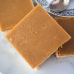 Ginger crunch 23 Close up of piece of ginger crunch stacked on top of other pieces, with a coffee saucer to the side.