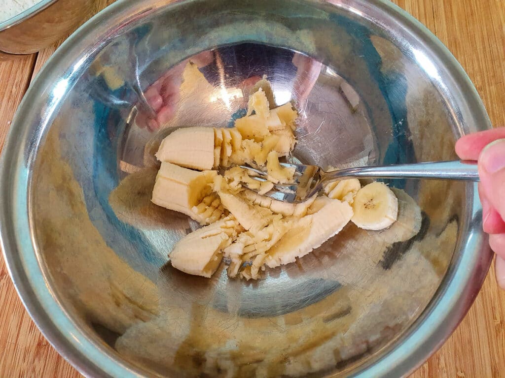 Banana pikelets 7 Mashing ripe banana with a fork.