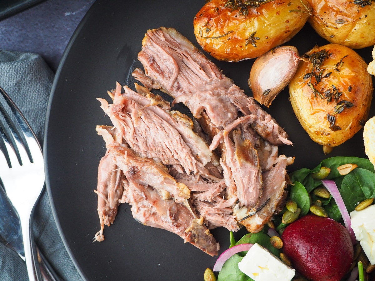Slow cooker lamb shoulder 14 Slow cooker lamb shoulder server on a plat, with roast potatoes and beetroot salad on the side.