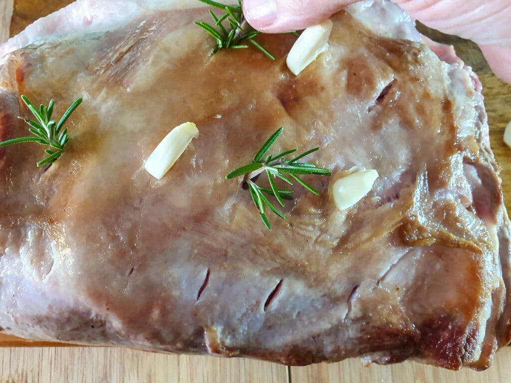 Slow cooker lamb shoulder 10 Inserting rosemary sprigs into cut slits in roast.