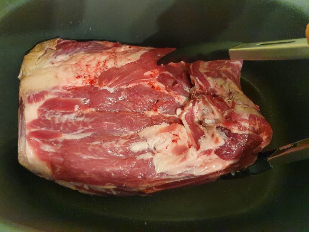 Slow cooker lamb shoulder 6 Turning the lamb over with tongs.