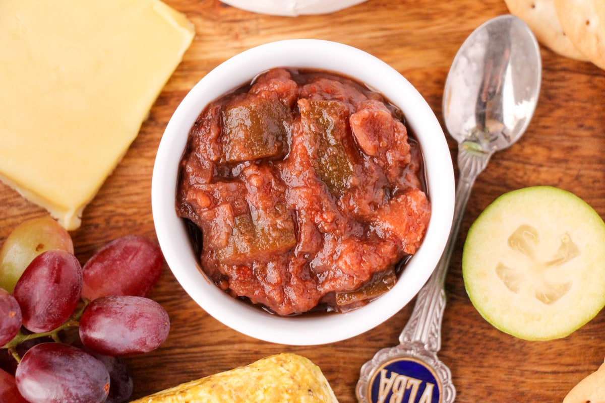 Feijoa chutney 17 Close up bowl of feijoa chutney on a cheeseboard with a serving spoon.