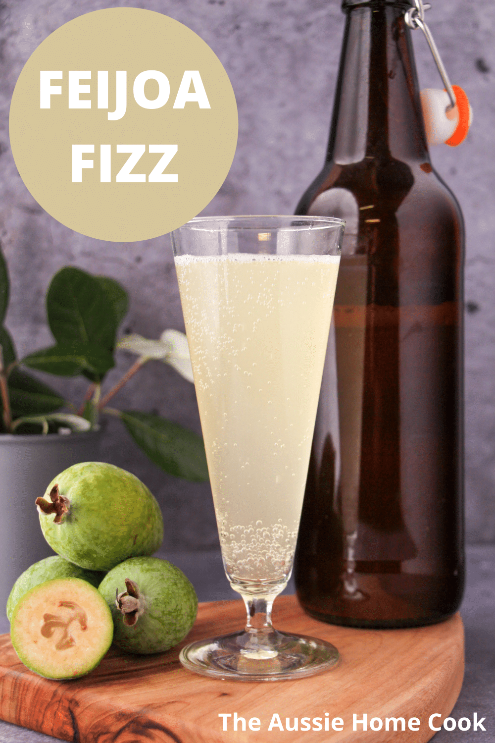 Feijoa fizz 14 Tall glass of feijoa fizz on a board, with bottle of feijoa fizz, fresh feijoas and feijoa leaves, with text overlay, feijoa fizz and The Aussie Home Cook.