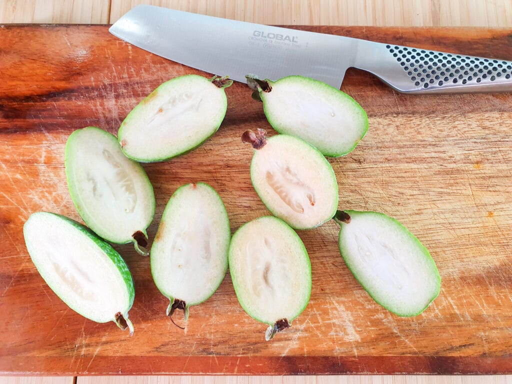 Slicing open feijoas length ways to scoop out flesh.