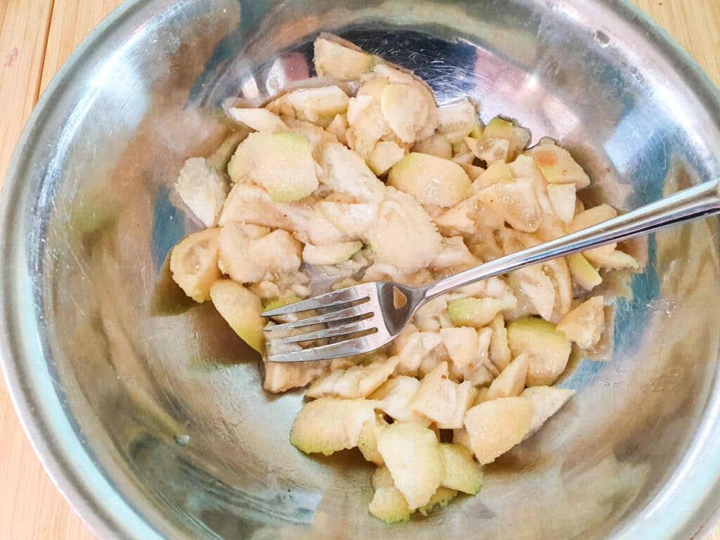 Lightly mashing feijoa flesh with a fork.