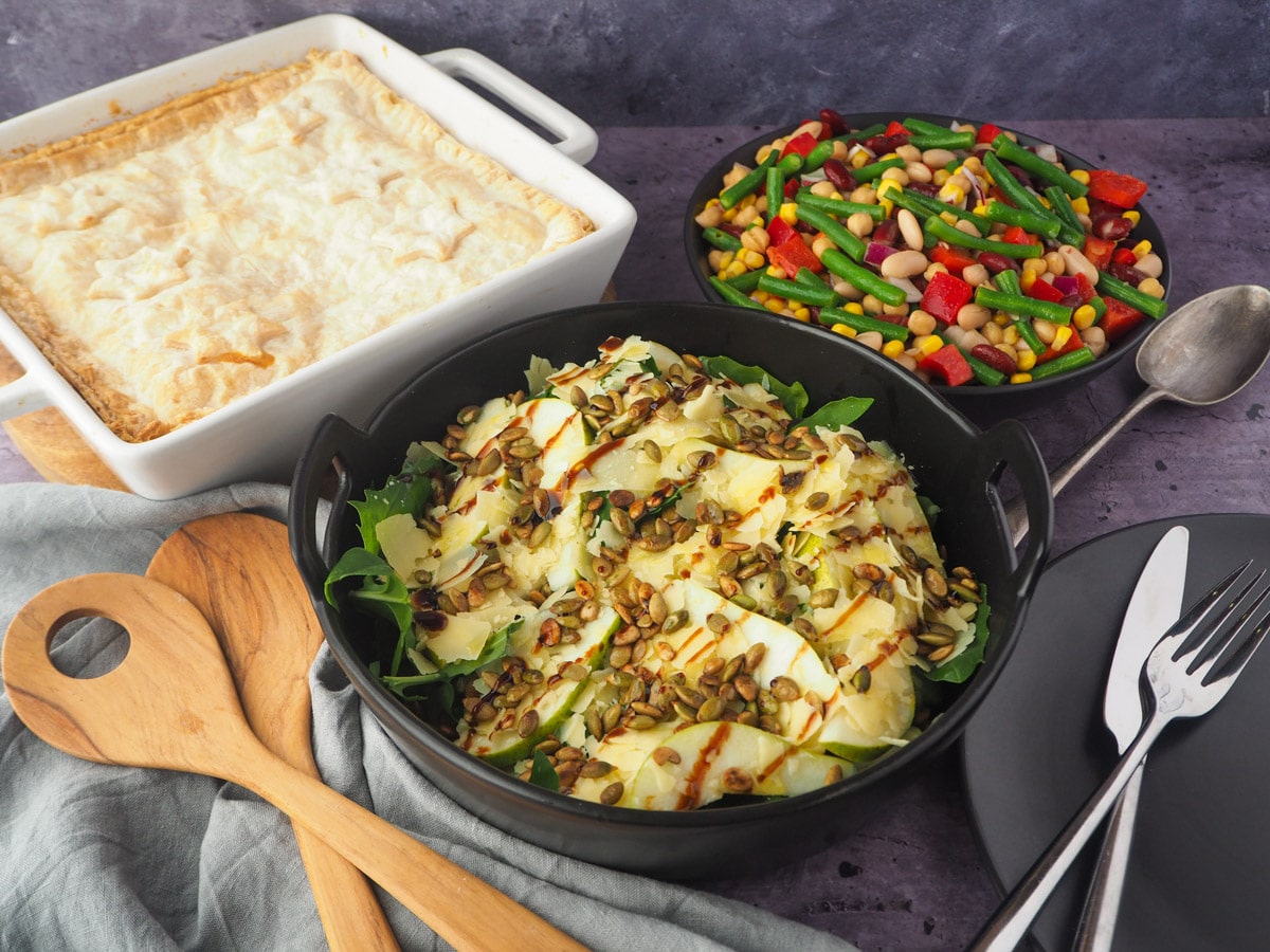 Rocket and Pear Salad 12 Salad with serving spoons, plate, knife and fork, pie and four bean salad in the background.