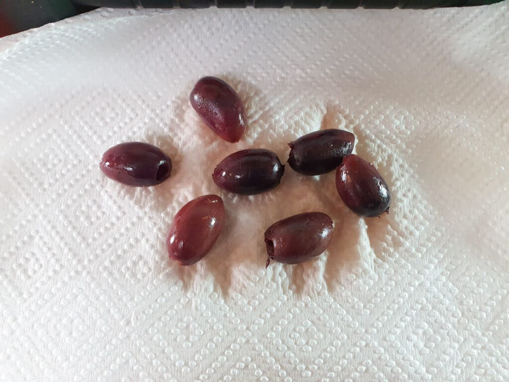 Picnic Charcuterie Board 6 Patting dry Kalamata olives.