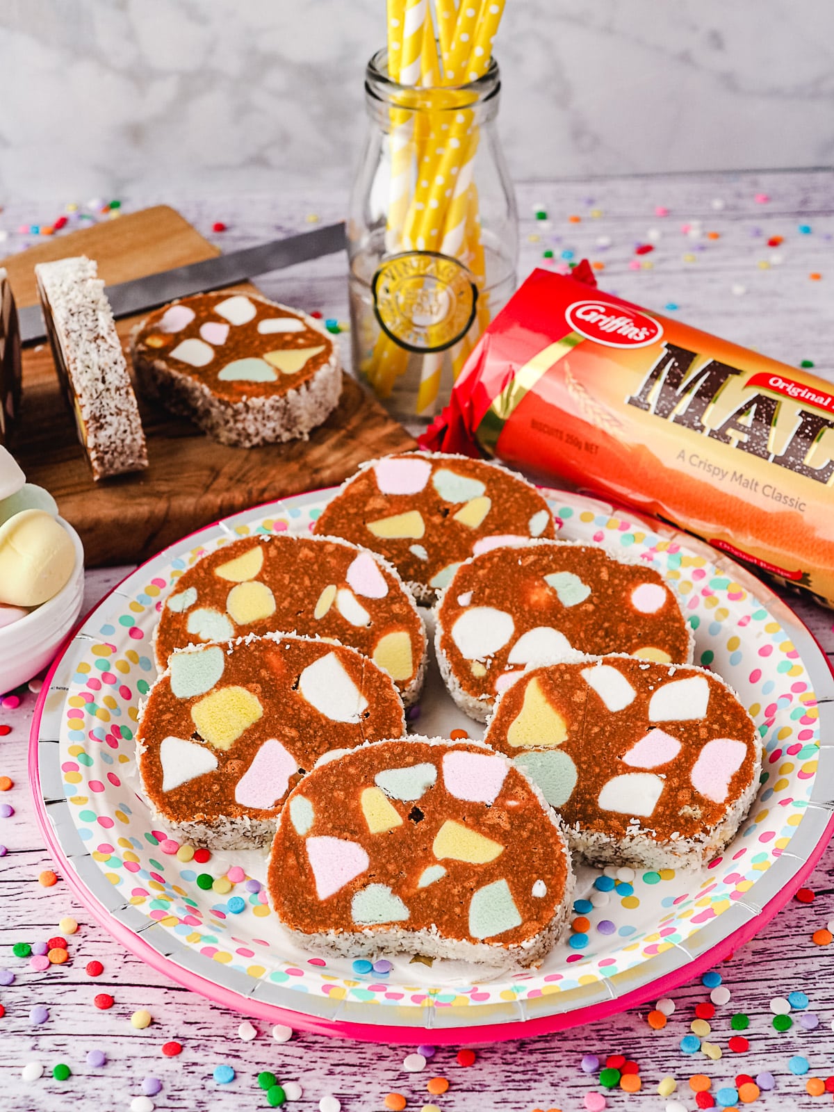 Lolly Cake 11 Slices of lolly cake on a plate, with sliced lolly cake and packet of malt biscuits in the background.