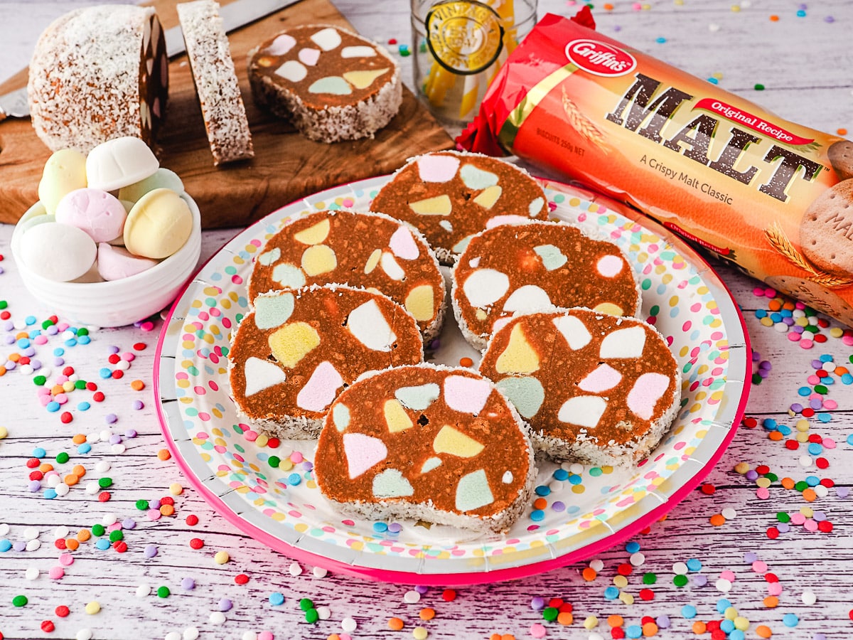 Lolly Cake 2 Slices of lolly cake on a plate, with sliced lolly cake and packet of malt biscuits in the background.
