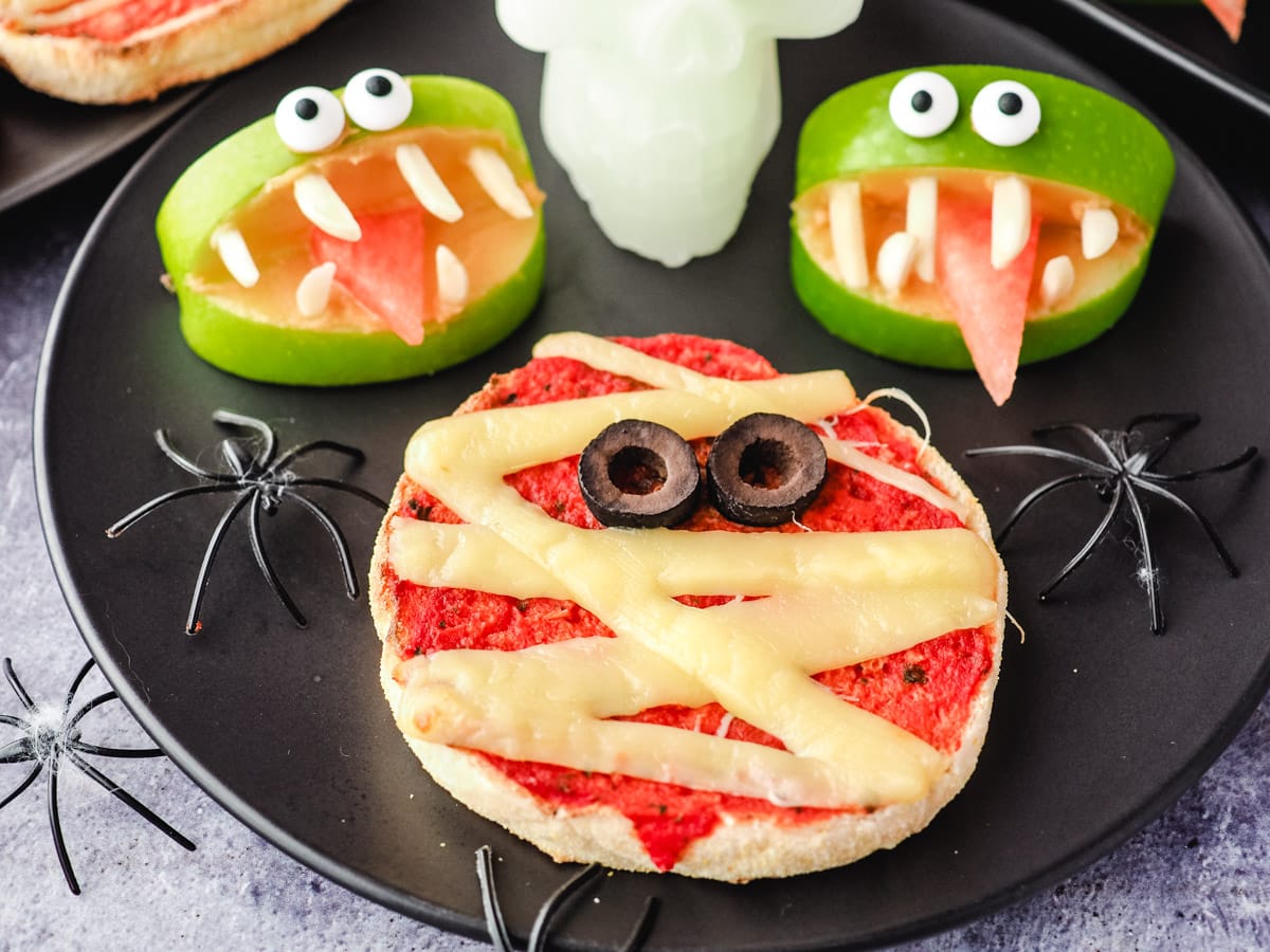 Mummy Pizzas 2 Pizza on a plate with apple monsters and skull and spider Halloween decorations