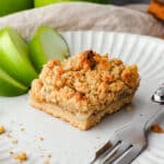 Apple Slice 10 Close up piece of apple slice on a plate with a fork and fresh apple on the side.