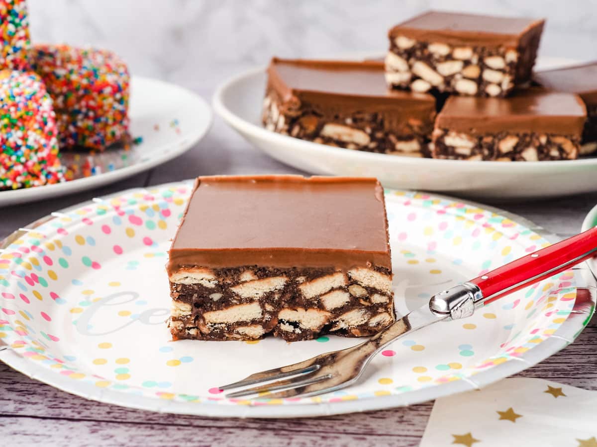 Hedgehog Slice 6 Piece of chocolate hedgehog slice on a plate with a fork, with party food in the backround.