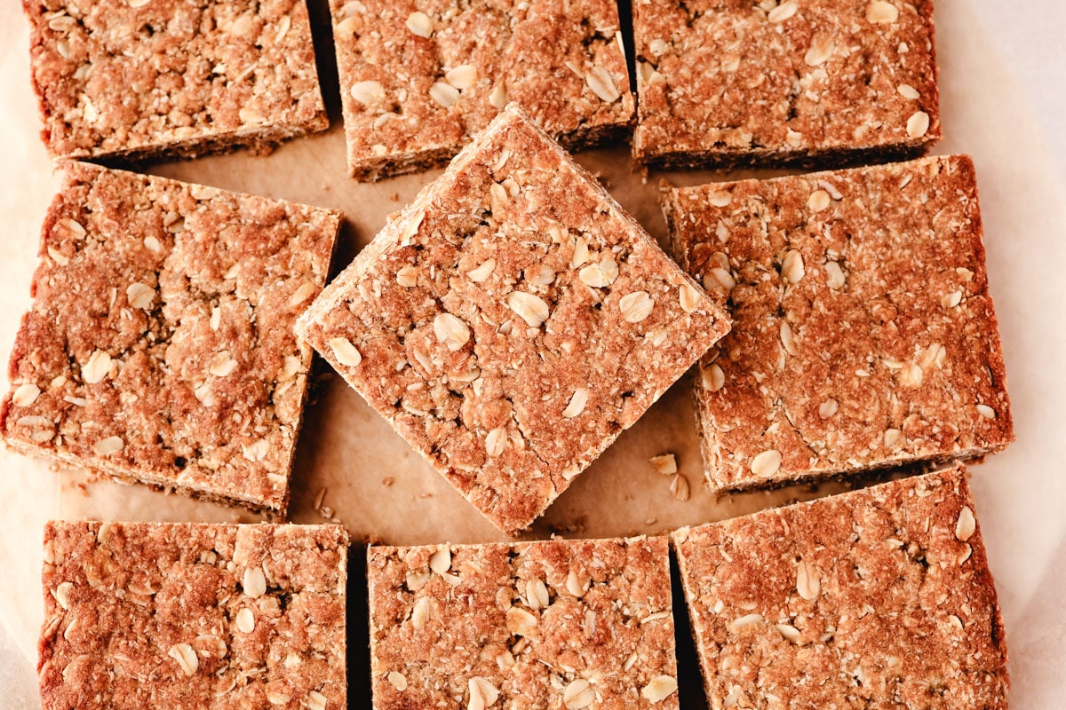 Anzac Slice 6 Top down shot of squares of Anzac slice on baking paper with the middle slice turned ninety degrees.